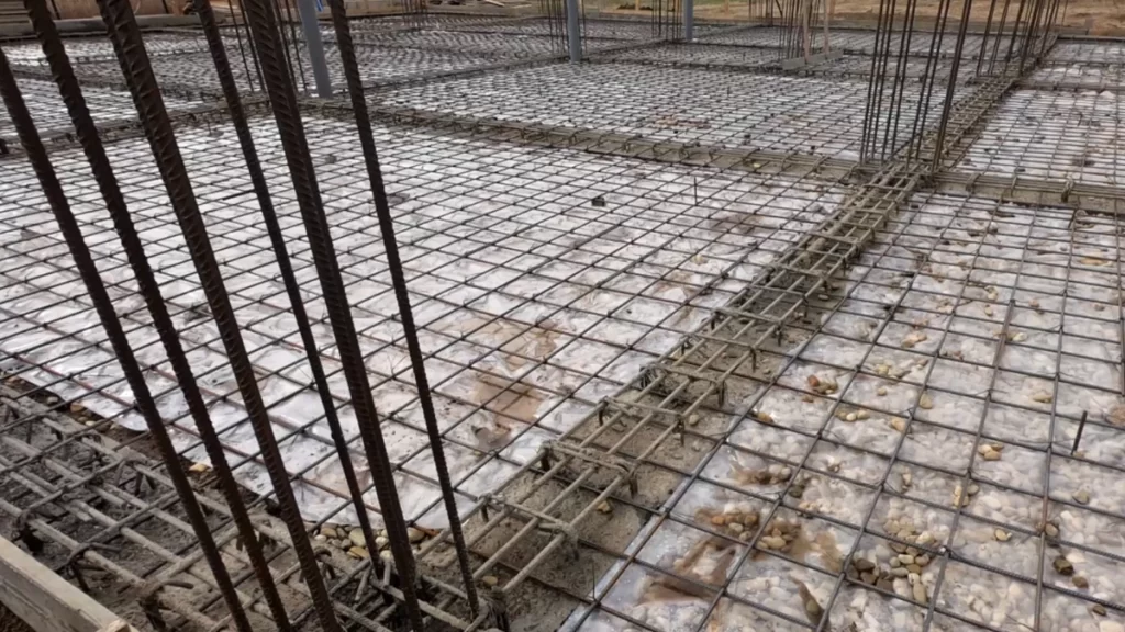 Plasă de armare pentru placa din beton și bare verticale pentru stâlpi, pe șantier, înainte de betonare.