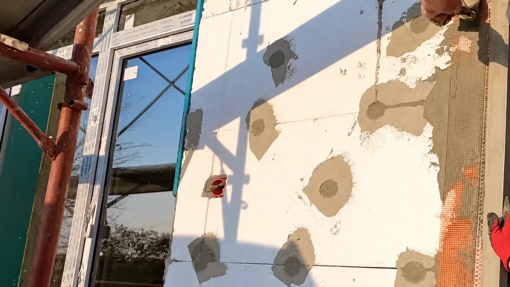 Termosistem cu polistiren EPS în curs de montaj pe fațada unei case.