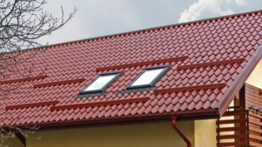 Acoperiș de casă cu țiglă metalică roșie Lindab și două ferestre de mansardă.