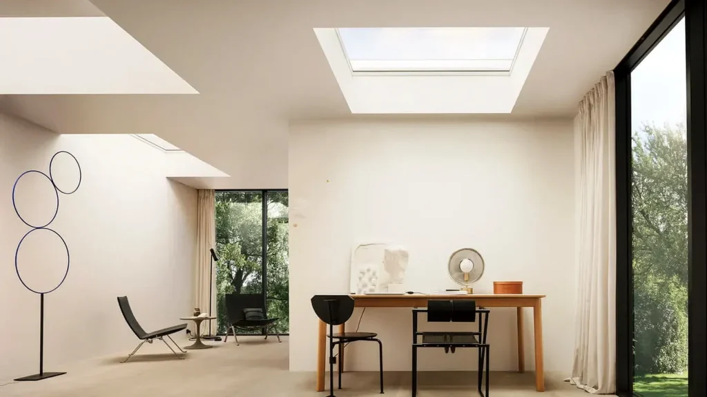Interior luminos cu ferestre VELUX montate în planul acoperișului, care aduc lumină naturală într-un spațiu de zi și birou.