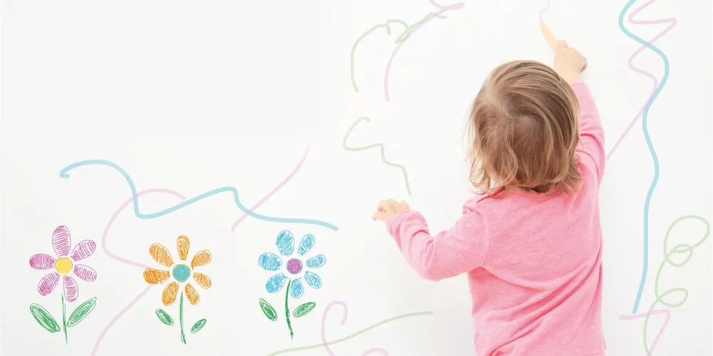 Copil desenând pe un perete interior lavabil într-o cameră luminoasă