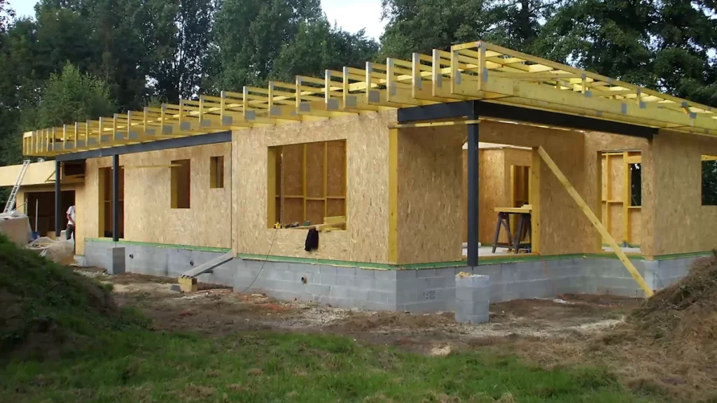 Casă în construcție, cu pereți placați cu OSB și elemente din lemn ale acoperișului.